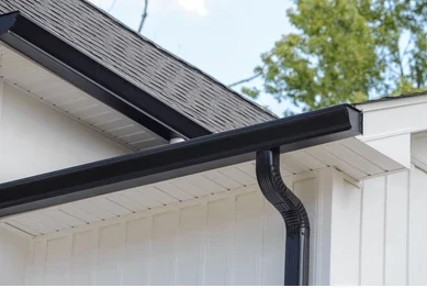 Black gutter and downspout on white house